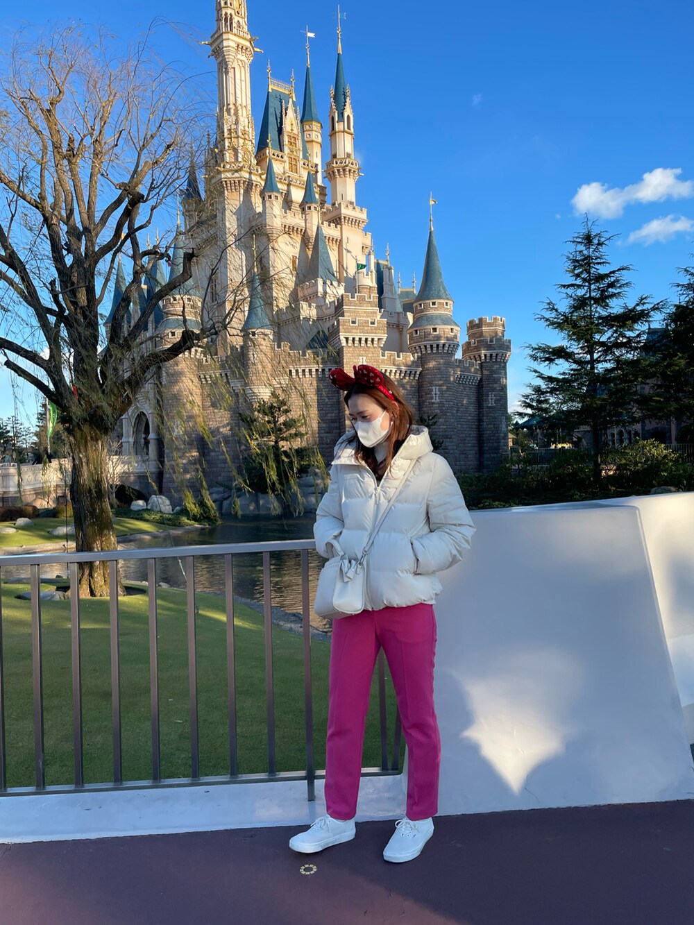 ピンク系のスラックス、ホワイト系のダウンジャケット/コート、ホワイト系のショルダーバッグを着用したレディースの冬コーディネートの2枚目の写真