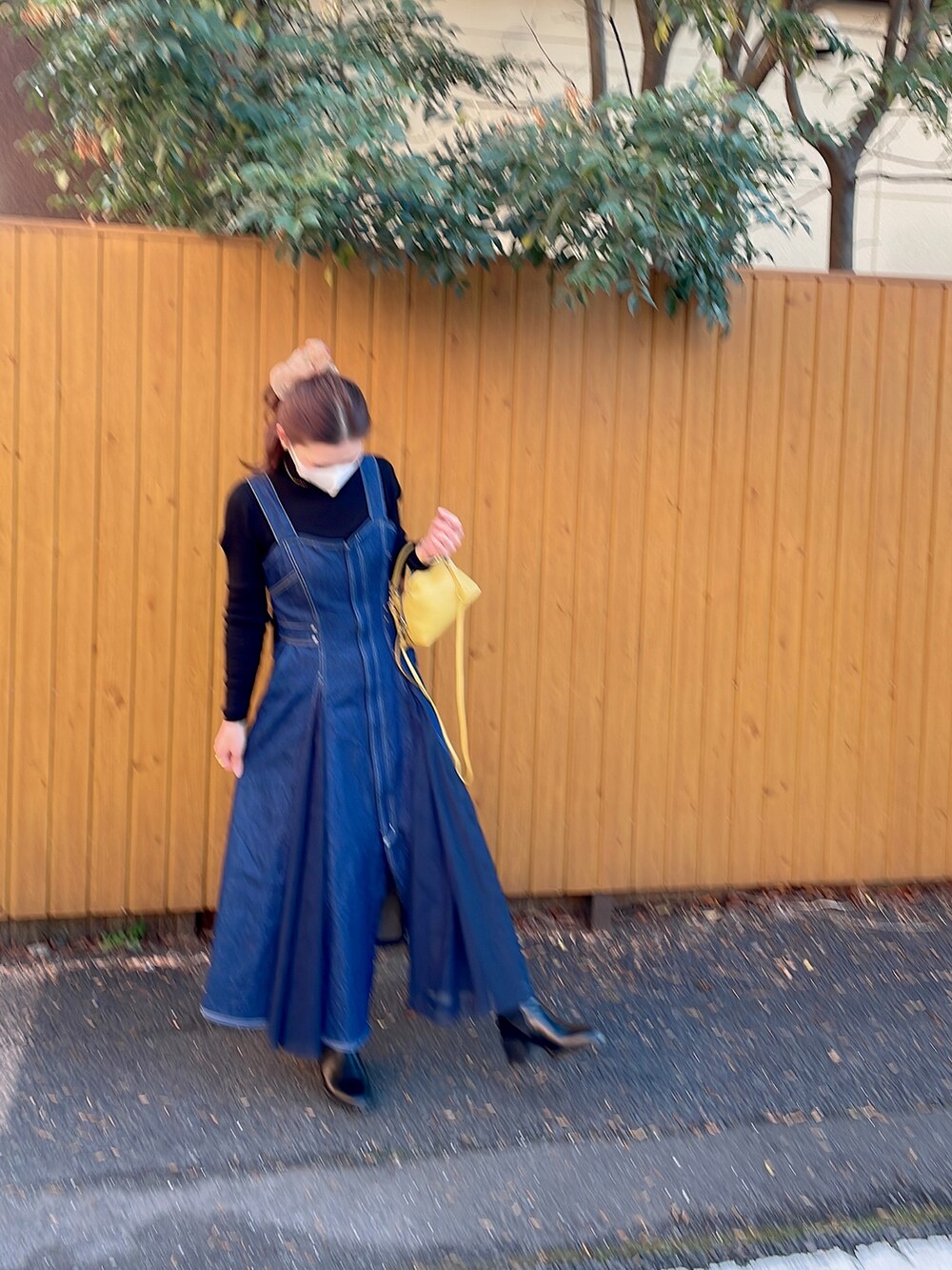 ブルー系のジャンパースカート、ブラック系のブーツ、イエロー系のショルダーバッグを着用したレディースの冬コーディネートの2枚目の写真