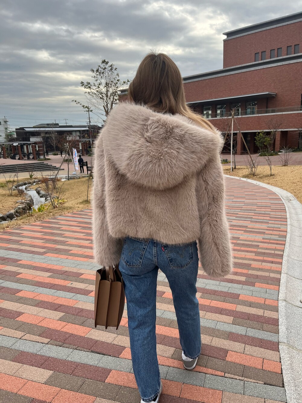 ブルー系のデニムパンツ、ベージュ系のその他アウター、グレー系のスニーカーを着用したレディースの冬コーディネートの3枚目の写真