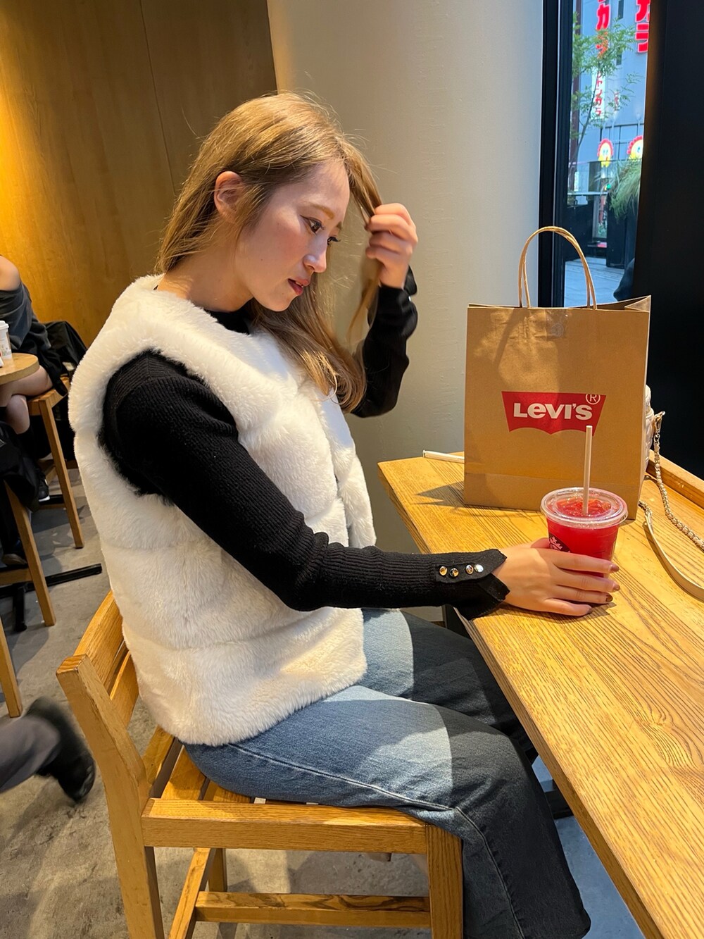 ホワイト系のベスト、ブルー系のデニムパンツ、ブラック系のニット/セーターを着用したレディースの秋コーディネートの2枚目の写真