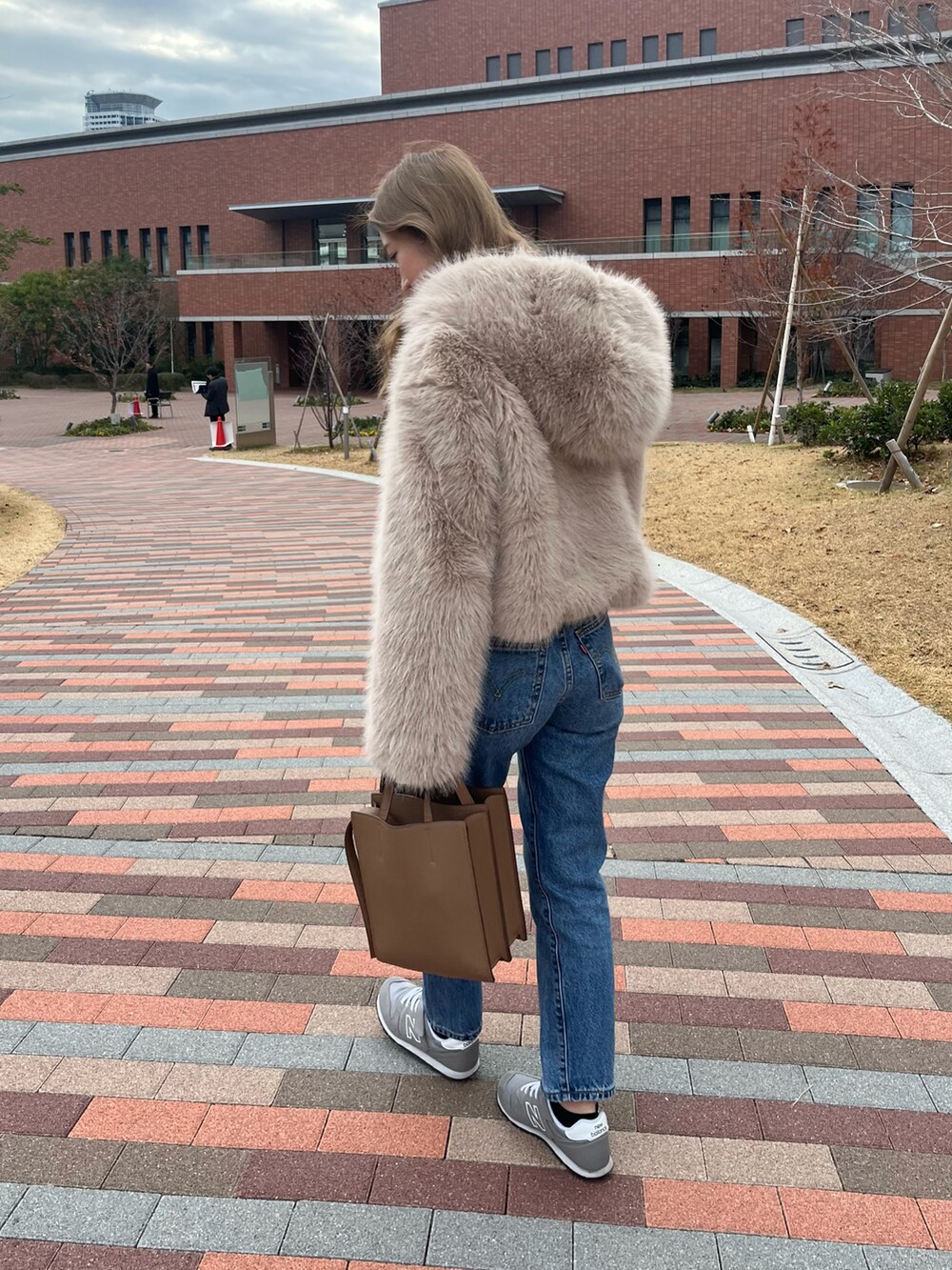 ブルー系のデニムパンツ、ベージュ系のその他アウター、グレー系のスニーカーを着用したレディースの冬コーディネートの2枚目の写真