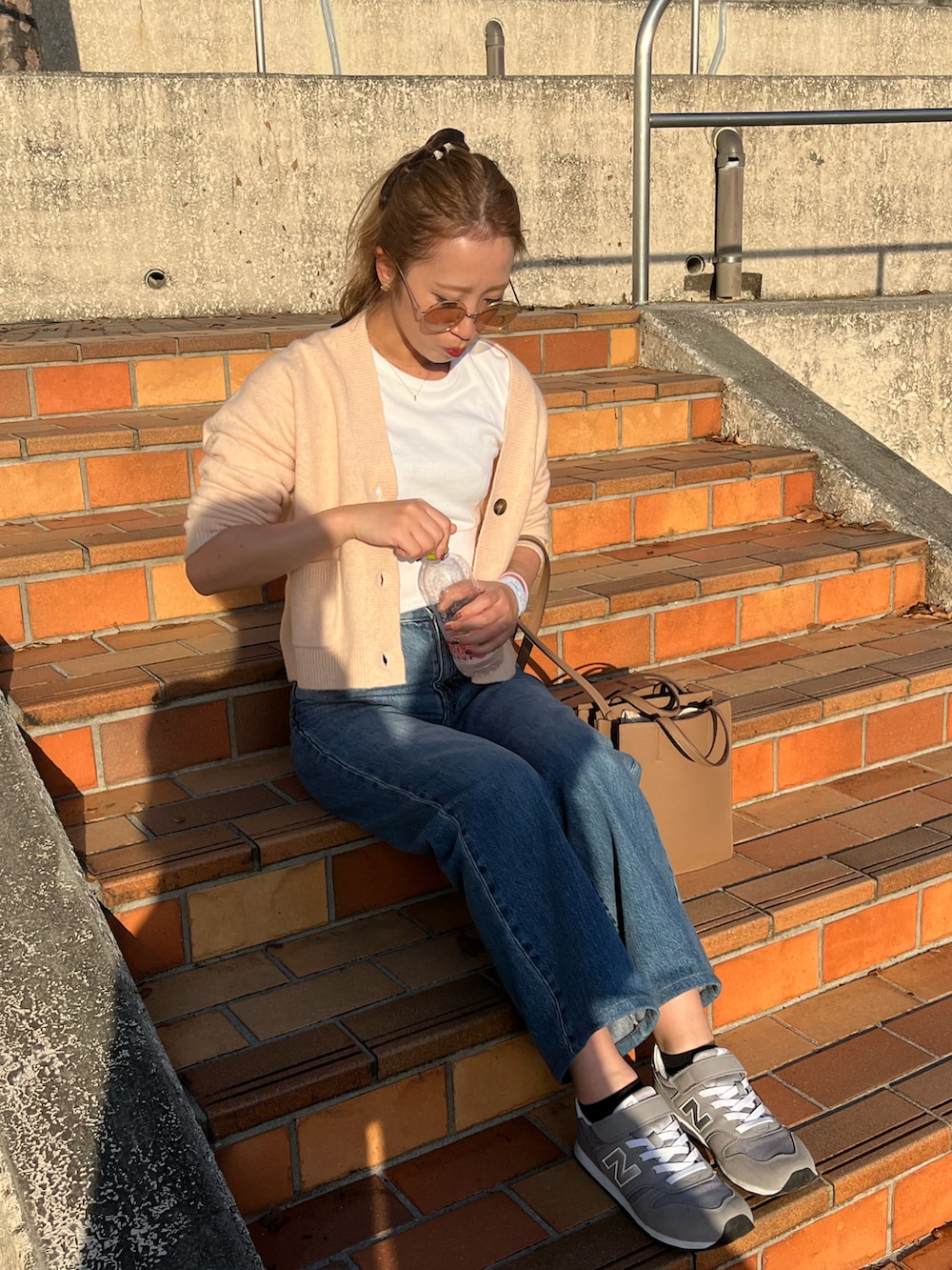 ブルー系のデニムパンツ、ホワイト系のTシャツ/カットソー、ピンク系のカーディガン/ボレロを着用したレディースの秋コーディネートの2枚目の写真