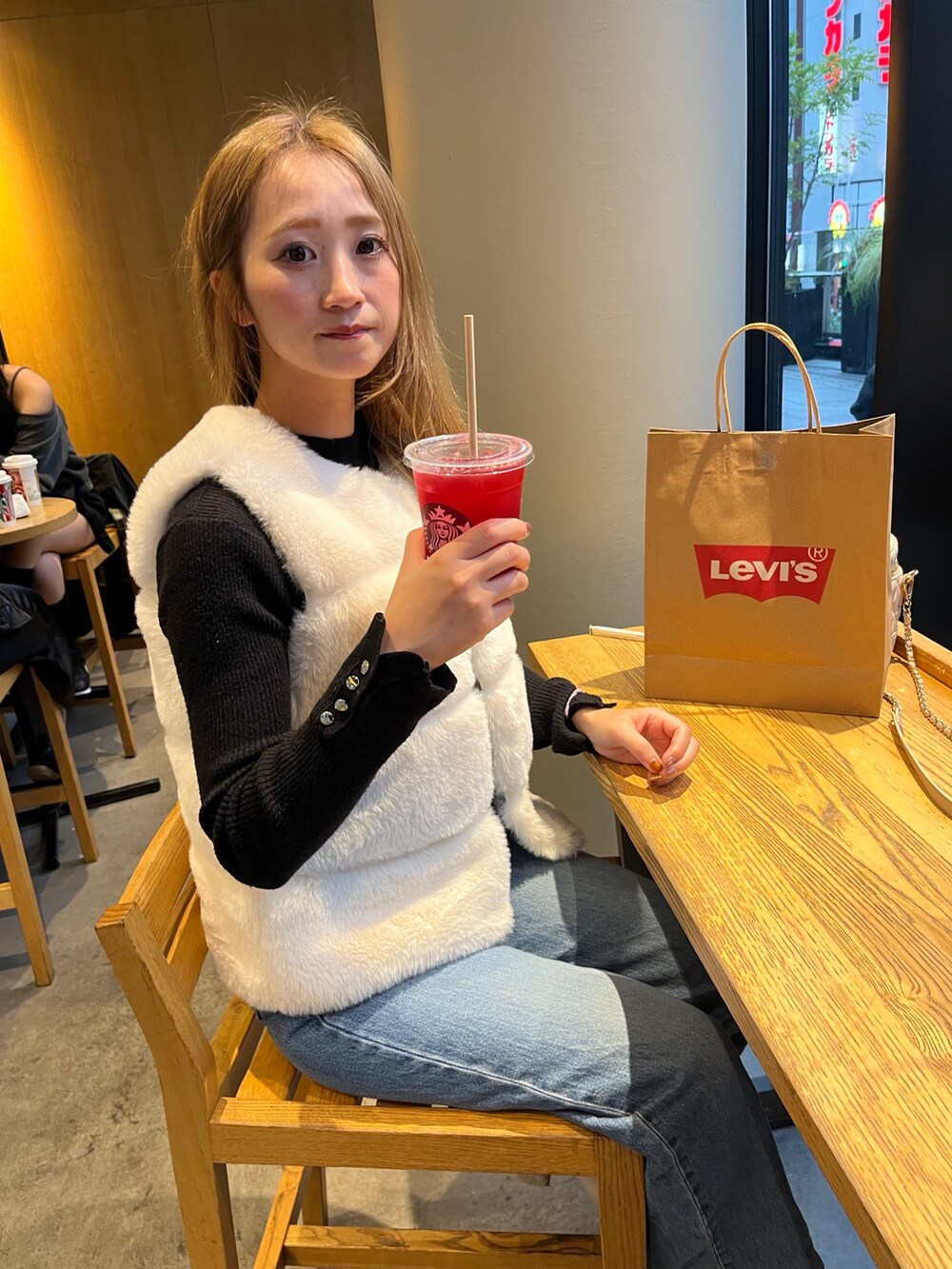 ホワイト系のベスト、ブルー系のデニムパンツ、ブラック系のニット/セーターを着用したレディースの秋コーディネートの3枚目の写真