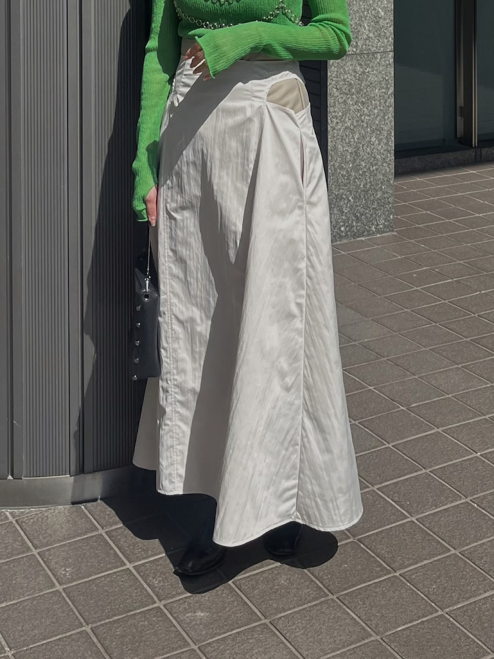 グリーン系のニット/セーター、ベージュ系のスカートを着用したレディースの春コーディネートの3枚目の写真