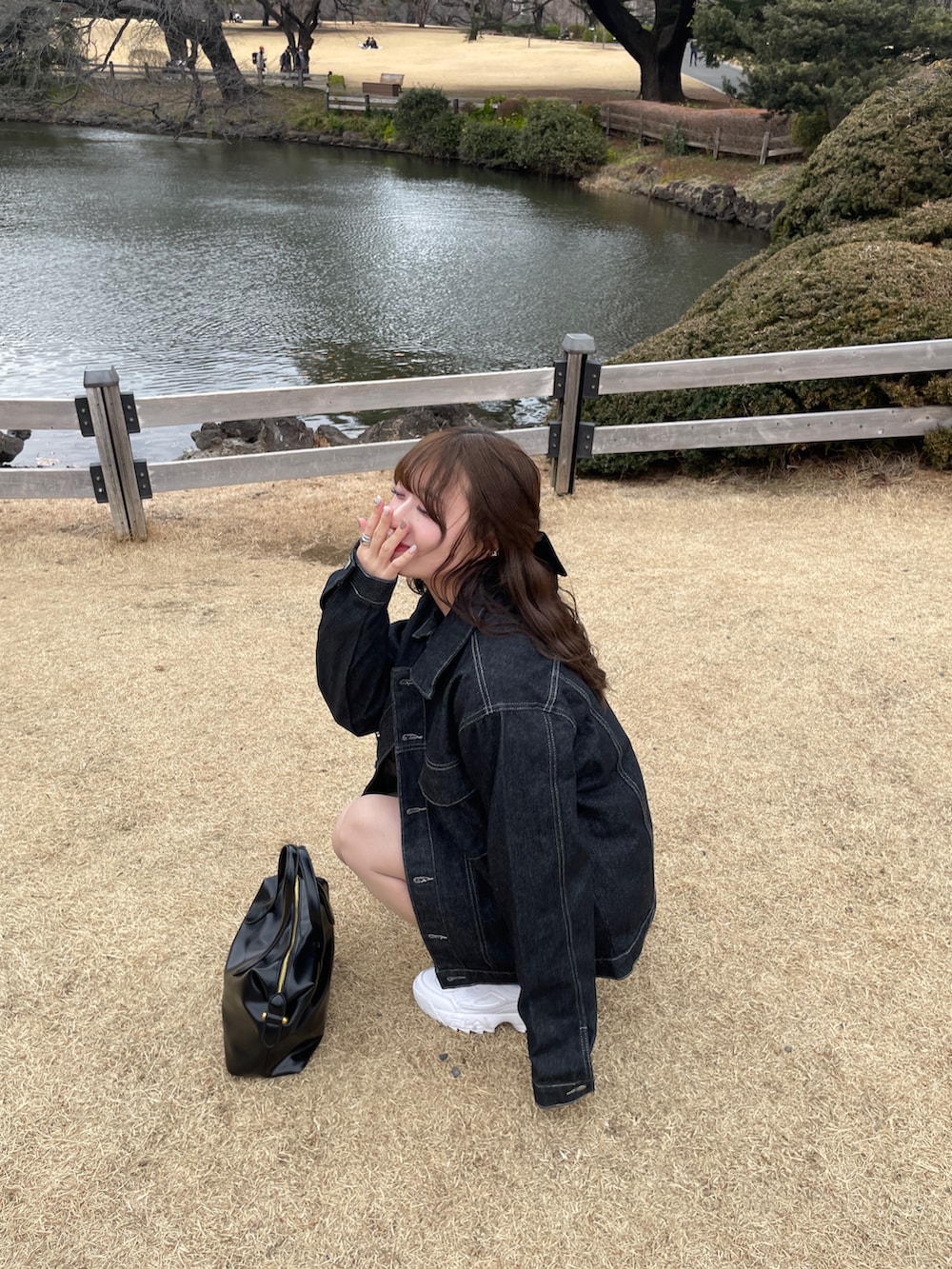 ホワイト系のスニーカー、ブルー系のデニムジャケット、ブラック系のハンドバッグを着用したレディースの冬コーディネートの3枚目の写真