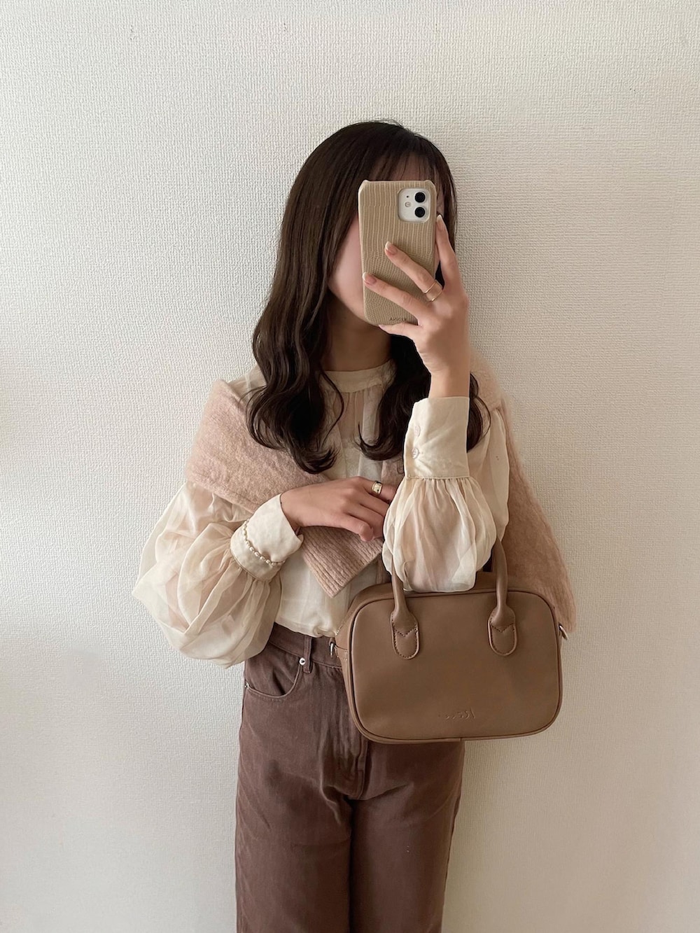 ホワイト系のシャツ/ブラウス、ピンク系のニット/セーター、ブラウン系のデニムパンツを着用したレディースの春コーディネートの2枚目の写真