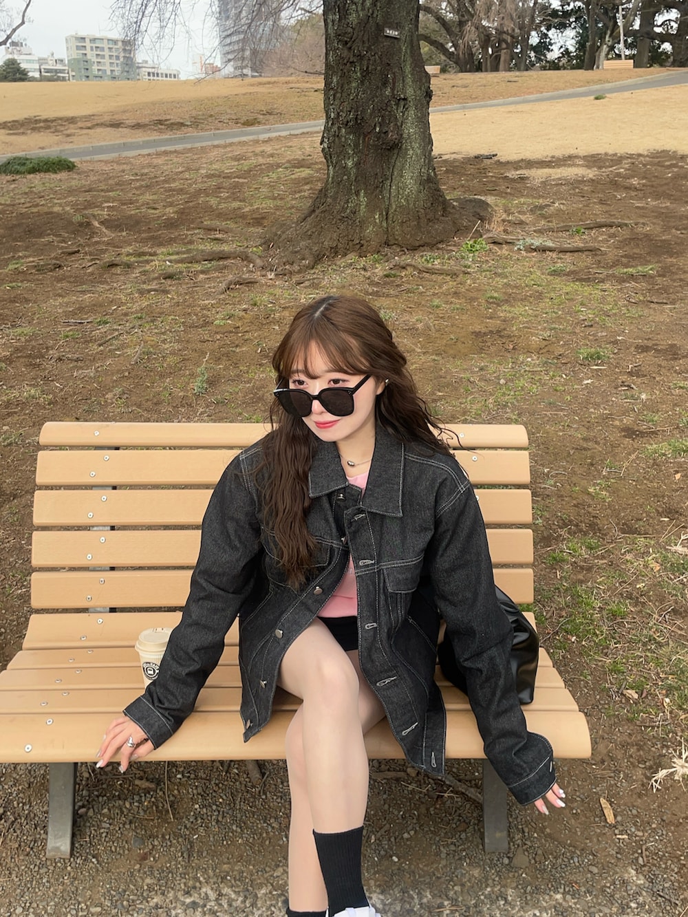 ホワイト系のスニーカー、ブルー系のデニムジャケット、ブラック系のハンドバッグを着用したレディースの冬コーディネートの4枚目の写真