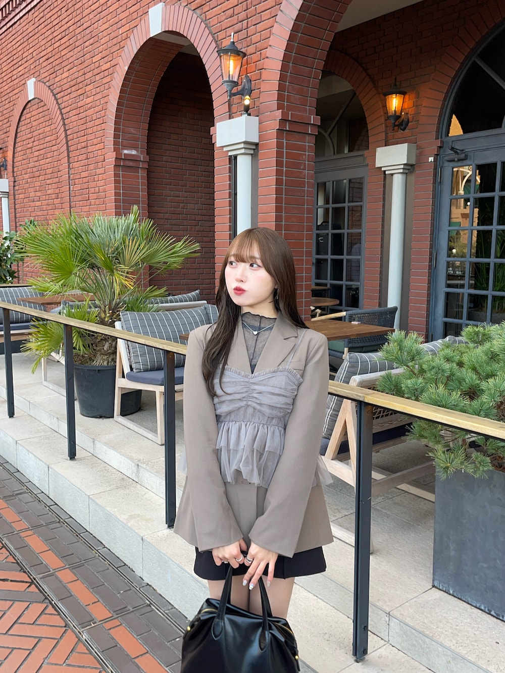 グレー系のキャミソール、ブラウン系のジャケット/アウター、ブラック系のハンドバッグを着用したレディースの冬コーディネートの2枚目の写真