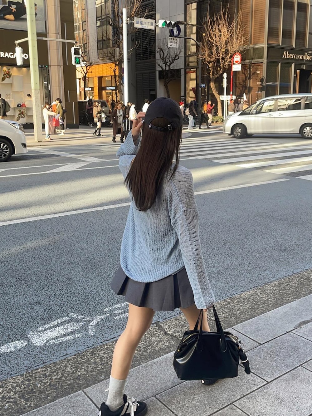 ブルー系のニット/セーター、ブラック系のハンドバッグ、ブラック系のスニーカーを着用したレディースの冬コーディネートの3枚目の写真