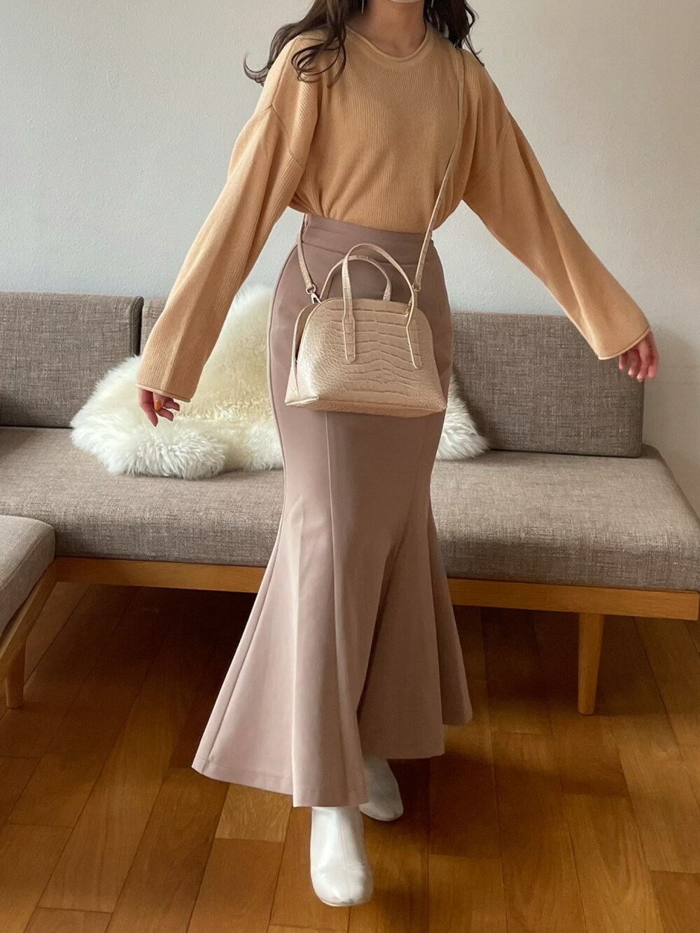 ベージュ系のスカート、ホワイト系のショルダーバッグ、オレンジ系のニット/セーターを着用したレディースの冬コーディネートの3枚目の写真