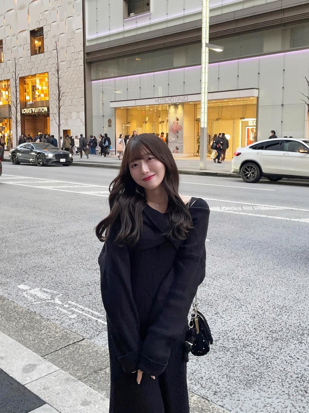 ブラック系のワンピース、ブラック系のショルダーバッグを着用したレディースの春コーディネートの2枚目の写真