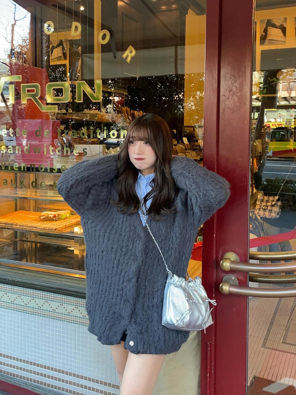 グレー系のカーディガン/ボレロ、ブルー系のシャツ/ブラウス、ブラック系のスニーカーを着用したレディースの冬コーディネートの2枚目の写真