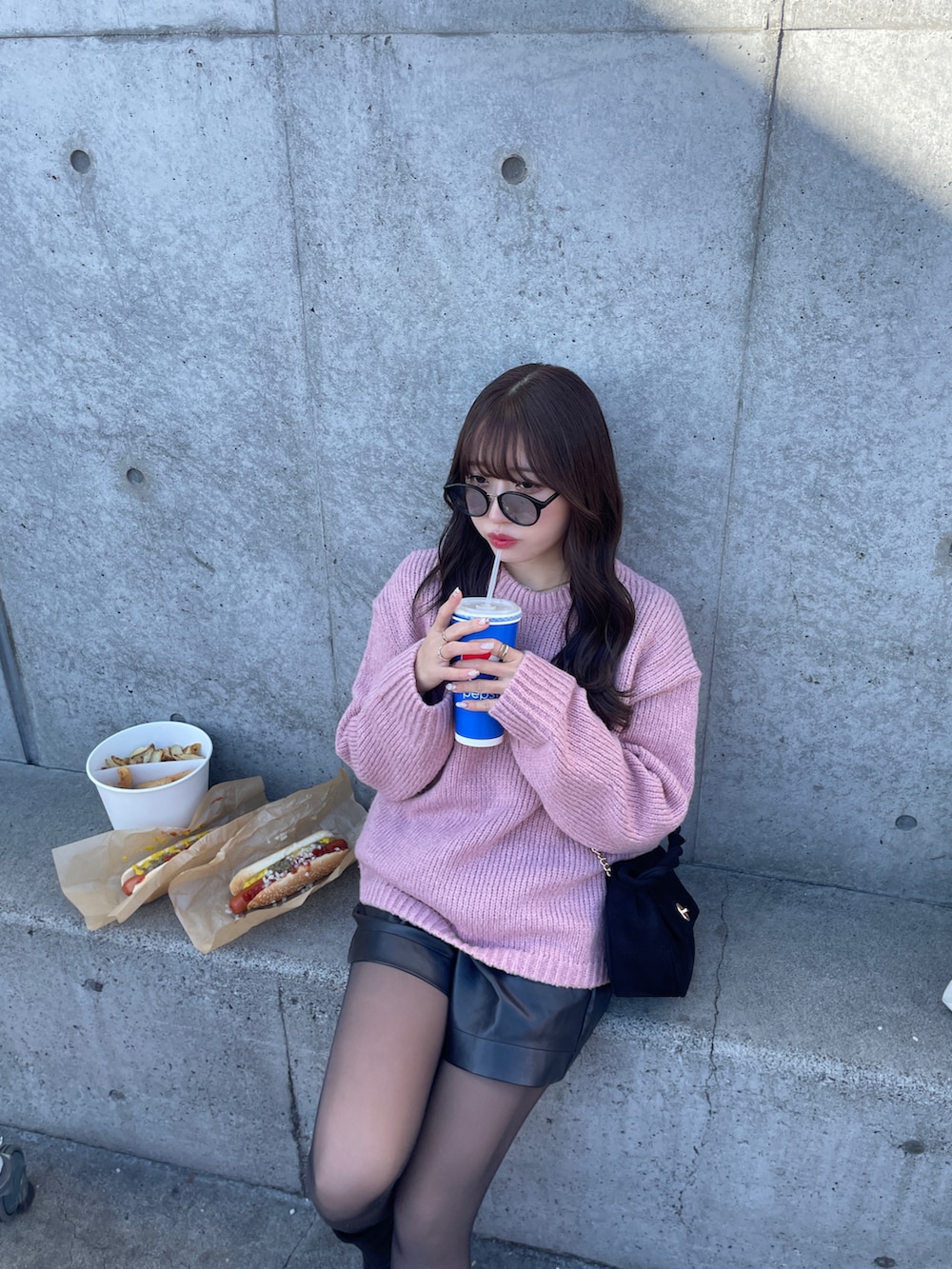 ピンク系のニット/セーター、ブラック系のパンツを着用したレディースの冬コーディネートの2枚目の写真