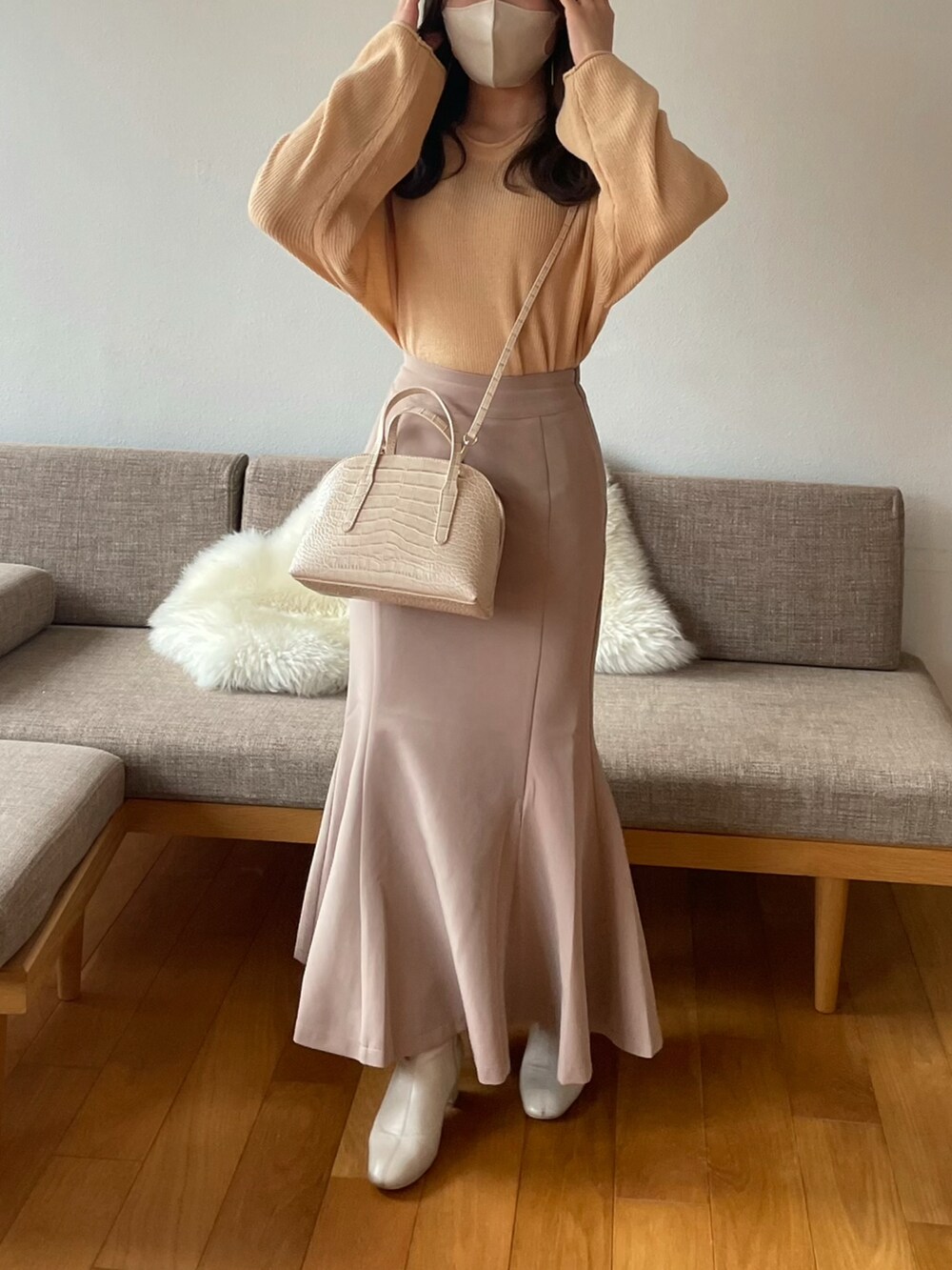 ベージュ系のスカート、ホワイト系のショルダーバッグ、オレンジ系のニット/セーターを着用したレディースの冬コーディネートの2枚目の写真