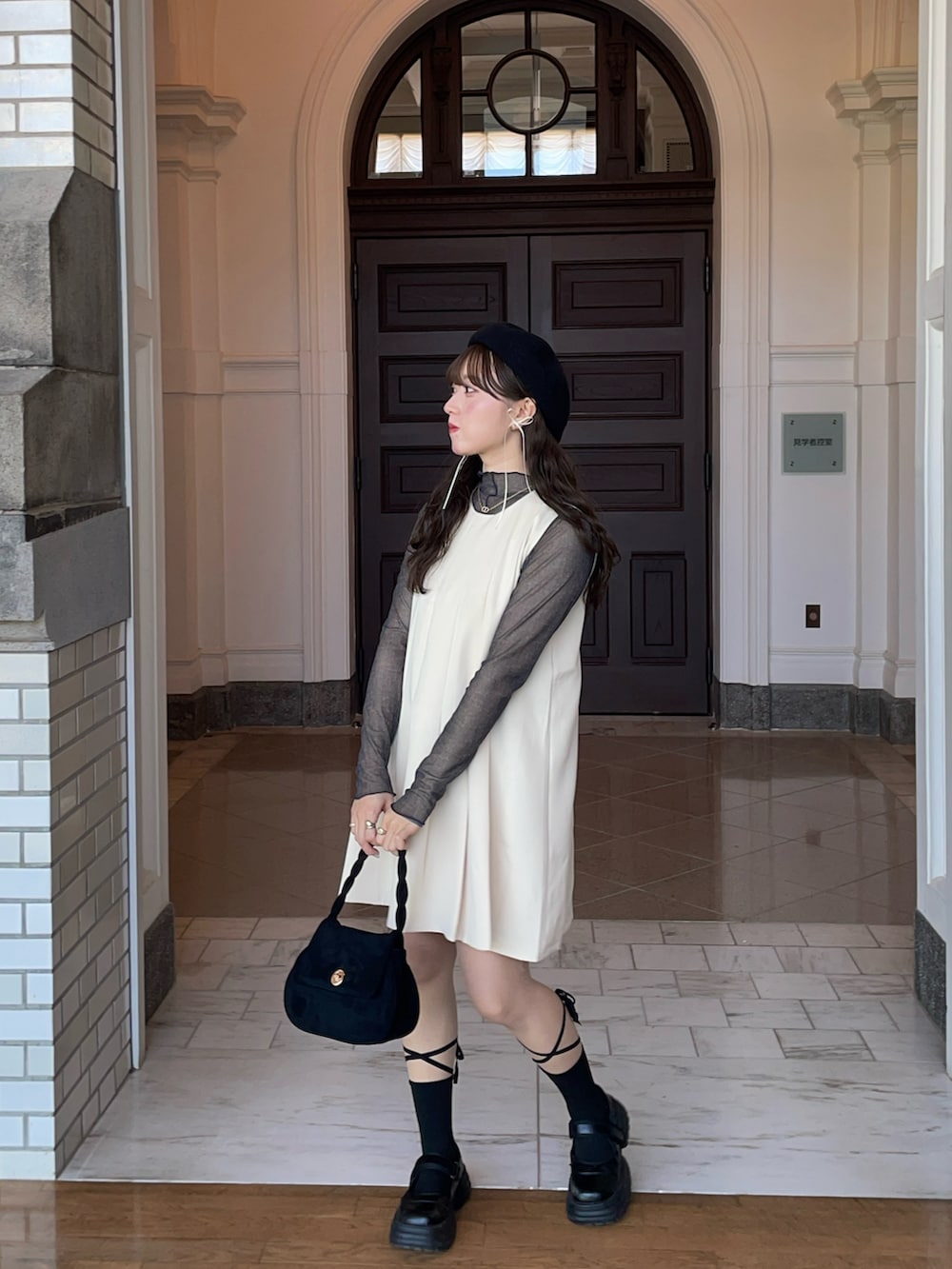 ベージュ系のワンピース、ブラック系のバッグ、ブラック系のスニーカーを着用したレディースの冬コーディネートの2枚目の写真