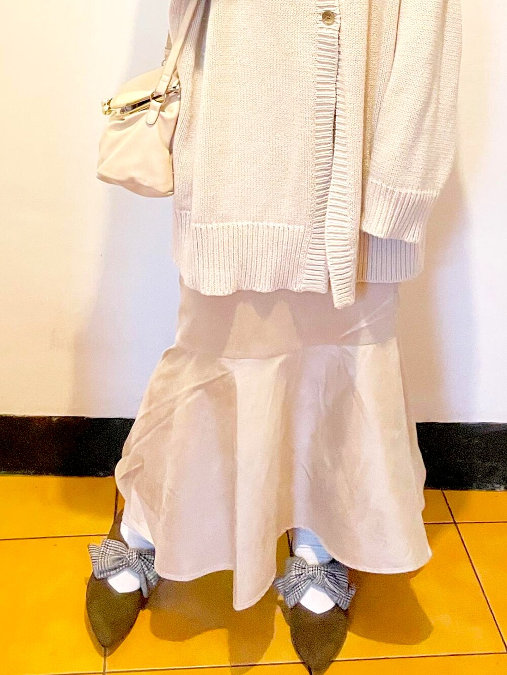 グレー系のニット/セーター、ベージュ系のスカート、ホワイト系のショルダーバッグを着用したレディースの冬コーディネートの3枚目の写真