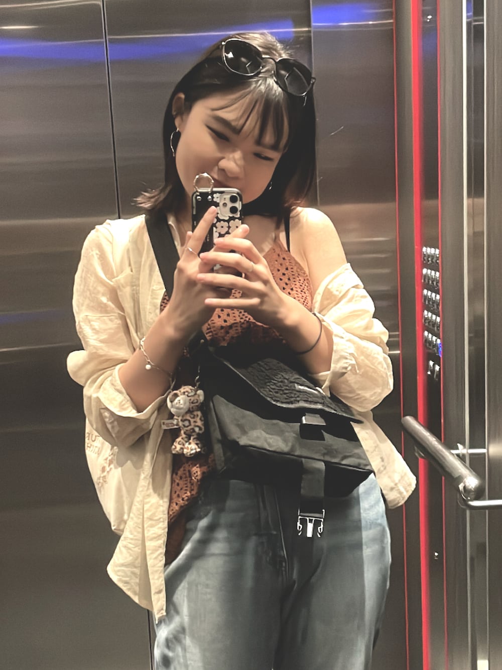 ブルー系のデニムパンツ、ブラウン系のトップス、ホワイト系のスニーカーを着用したレディースの春コーディネートの2枚目の写真