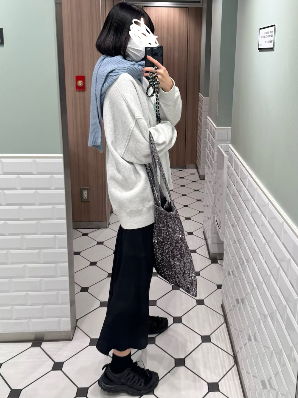 シルバー系のトートバッグ、ブラック系のスニーカー、ブルー系のマフラーを着用したレディースの秋コーディネートの2枚目の写真