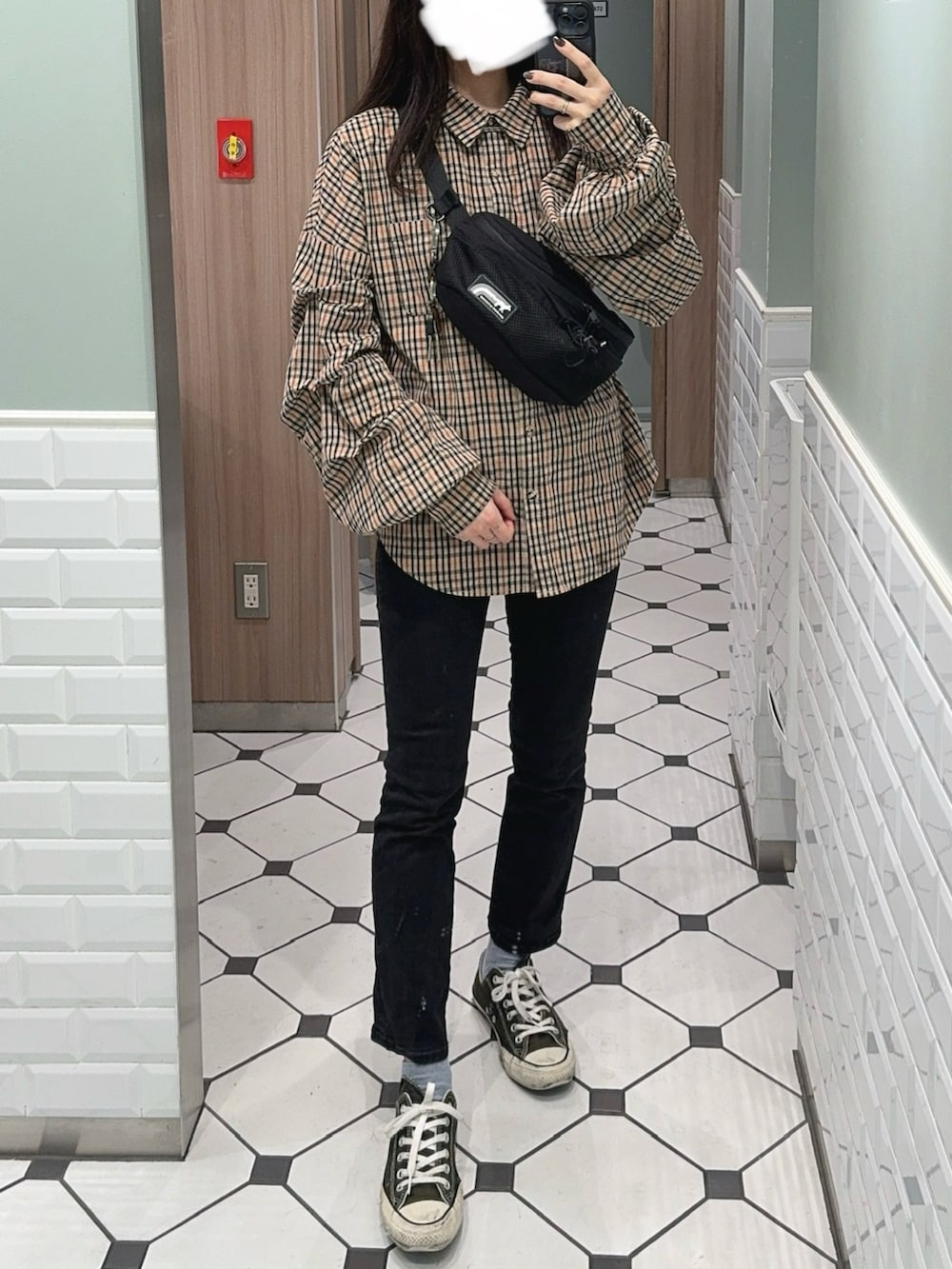 ブラック系のボディバッグ/ウエストポーチ、ホワイト系のタンクトップ、ブラック系のデニムパンツを着用したレディースの秋コーディネートの3枚目の写真