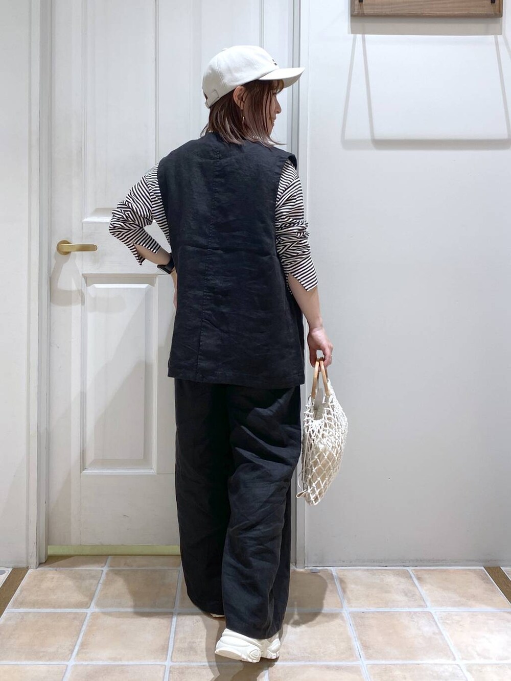 ベージュ系のスニーカー、ブラック系のその他パンツ、ブラック系のベストを着用したレディースの春コーディネートの6枚目の写真