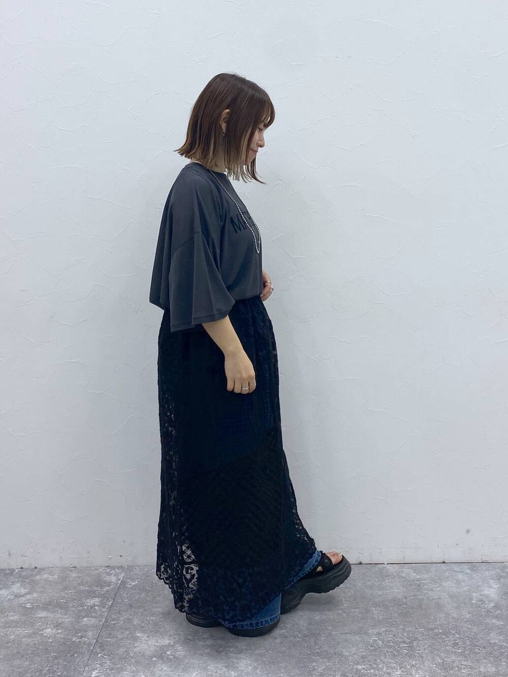 ブラック系のサンダル、ブルー系のデニムパンツ、ブラック系のスカートを着用したレディースの秋コーディネートの4枚目の写真