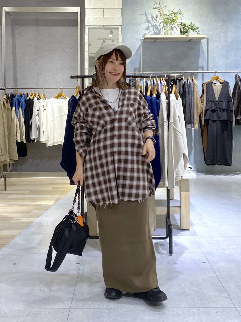 ブラック系のショルダーバッグ、ブラウン系のスカート、ブラック系のスニーカーを着用したレディースの秋コーディネートの2枚目の写真