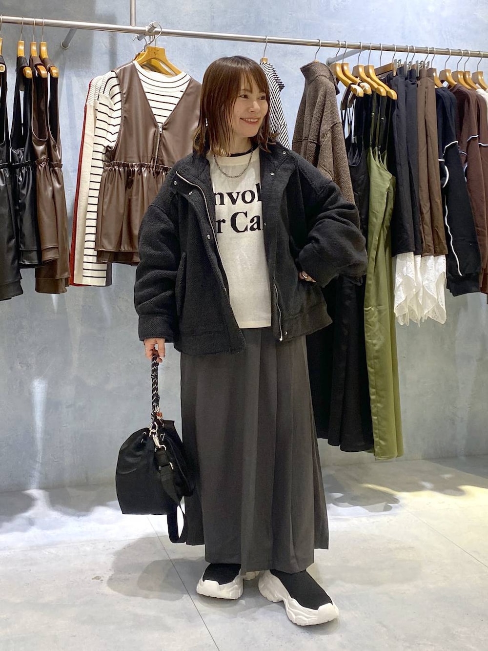 ブラック系のショルダーバッグ、ブラック系のニット/セーター、ホワイト系のニット/セーターを着用したレディースの秋コーディネートの2枚目の写真