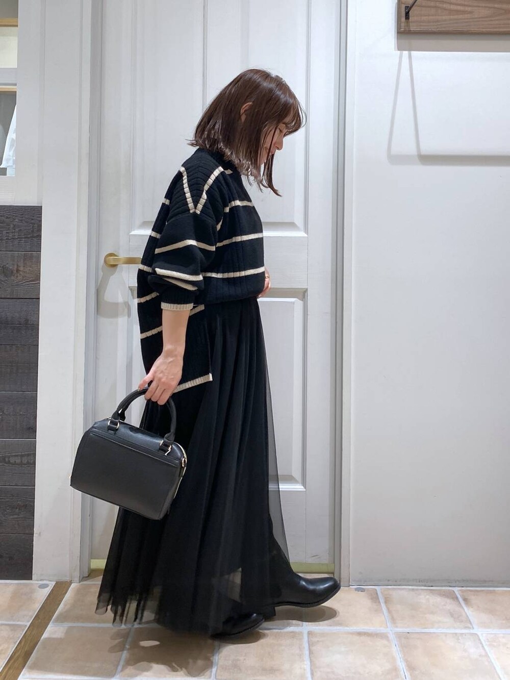 ブラック系のブーツ、その他のニット/セーター、ブラック系のスカートを着用したレディースの冬コーディネートの5枚目の写真