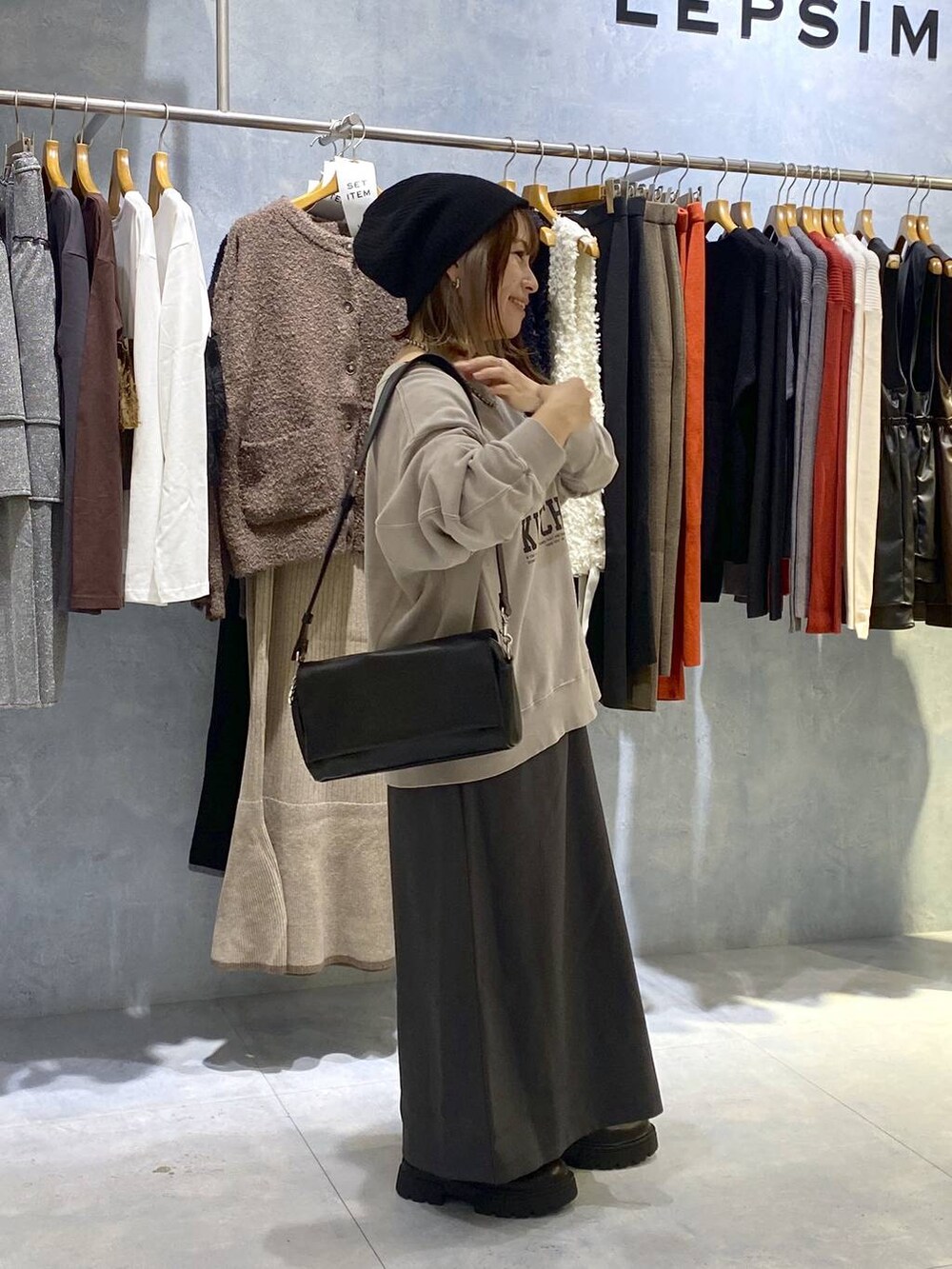 ブラック系のショルダーバッグ、ブラック系のブーツ、グレー系のスカートを着用したレディースの秋コーディネートの4枚目の写真