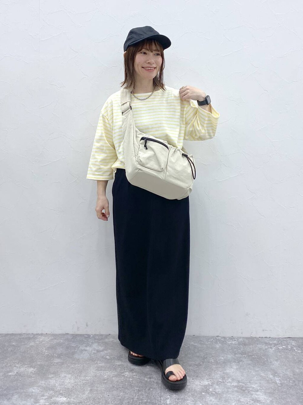 ホワイト系のショルダーバッグ、ブラック系のスカート、シルバー系のネックレスを着用したレディースの春コーディネートの3枚目の写真