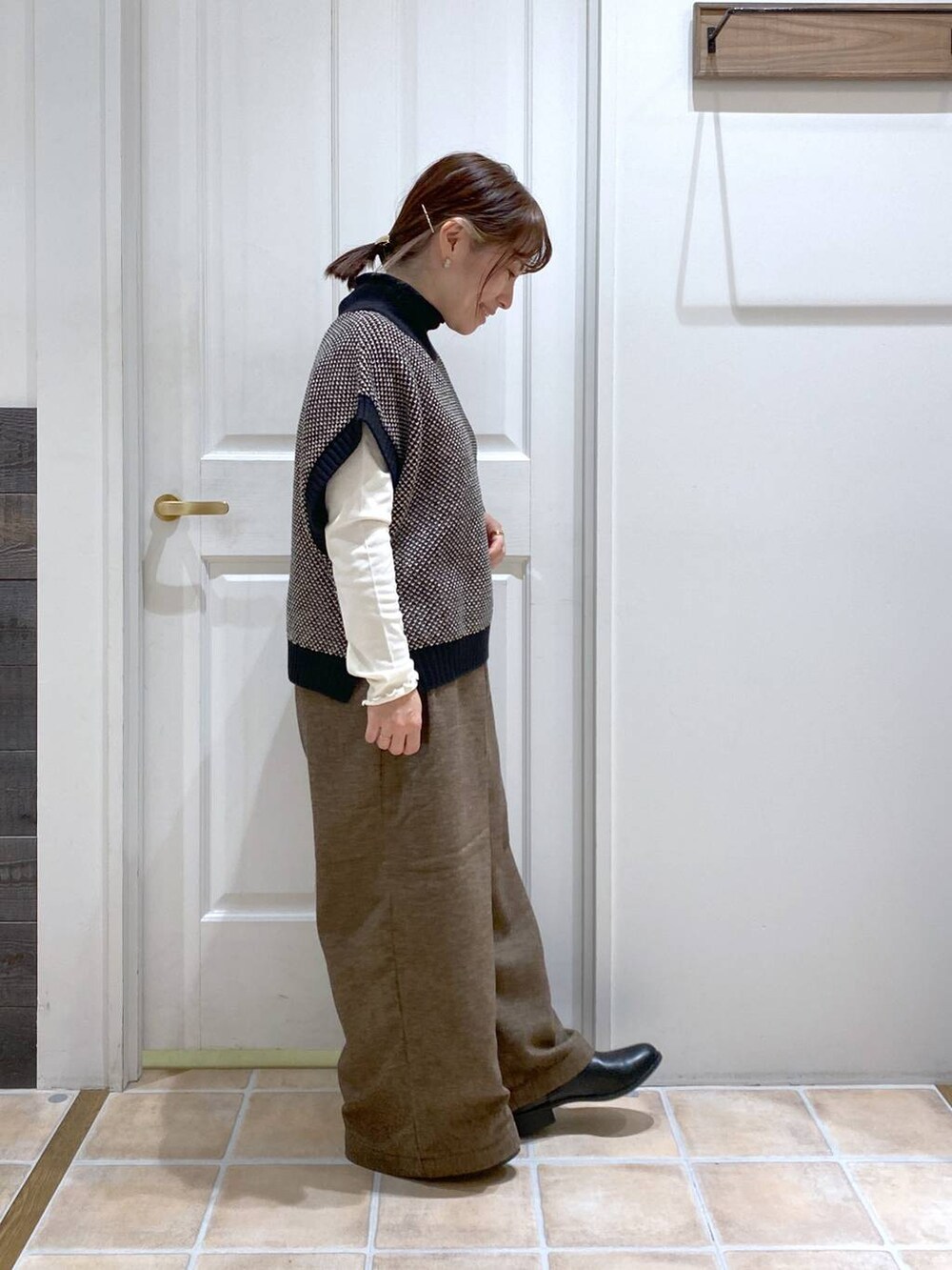 ホワイト系のTシャツ/カットソー、ブラック系のブーツ、ブラック系のベストを着用したレディースの秋コーディネートの4枚目の写真