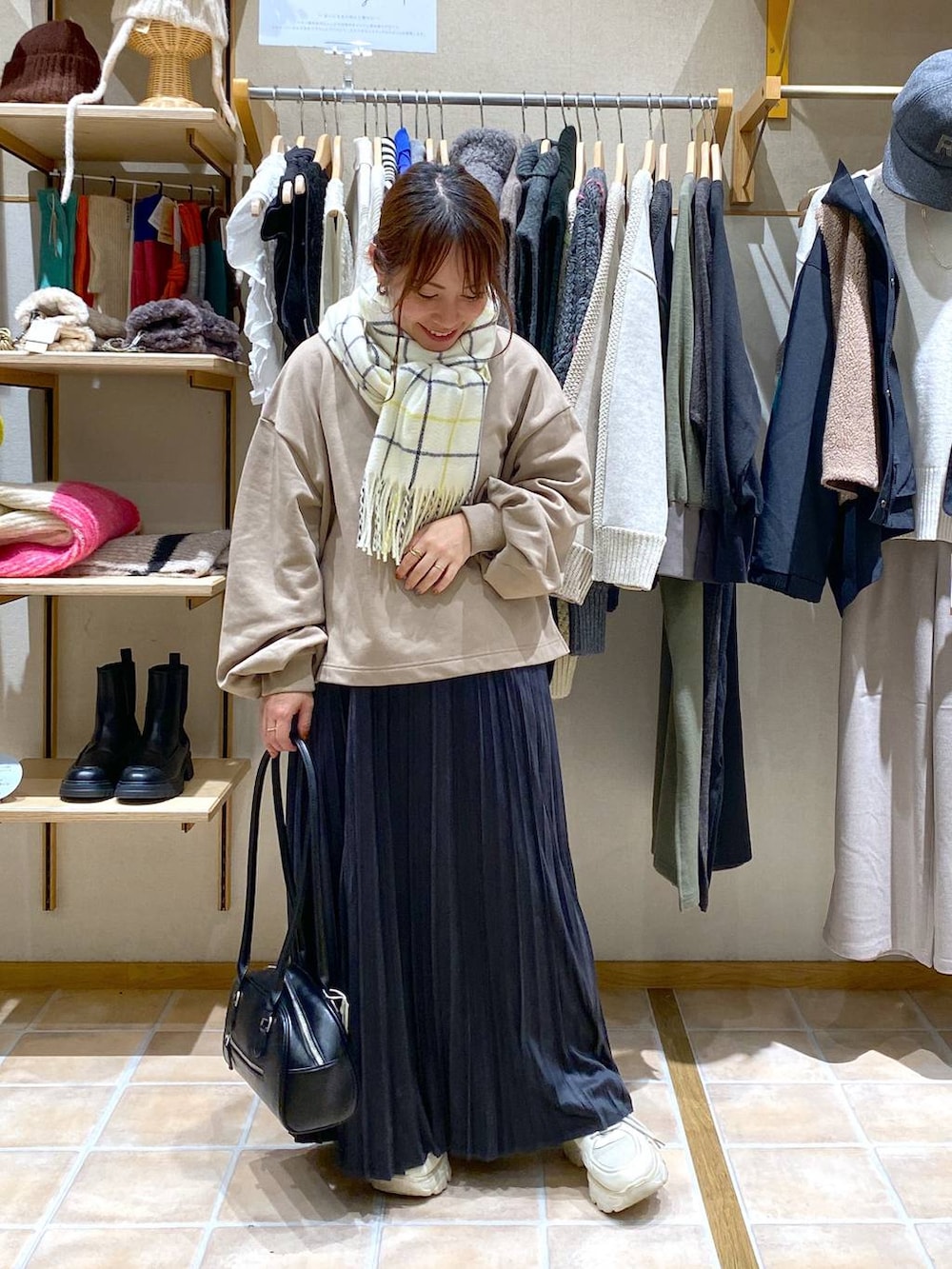 グレー系のスカート、ブラック系のトートバッグ、ベージュ系のTシャツ/カットソーを着用したレディースの冬コーディネートの2枚目の写真