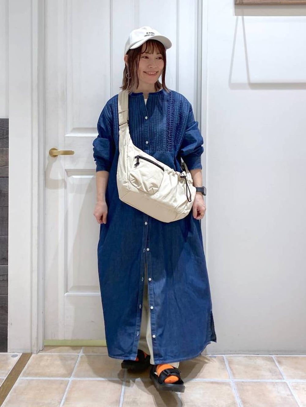 ブラック系のサンダル、ホワイト系のショルダーバッグ、ブルー系のワンピースを着用したレディースの春コーディネートの2枚目の写真