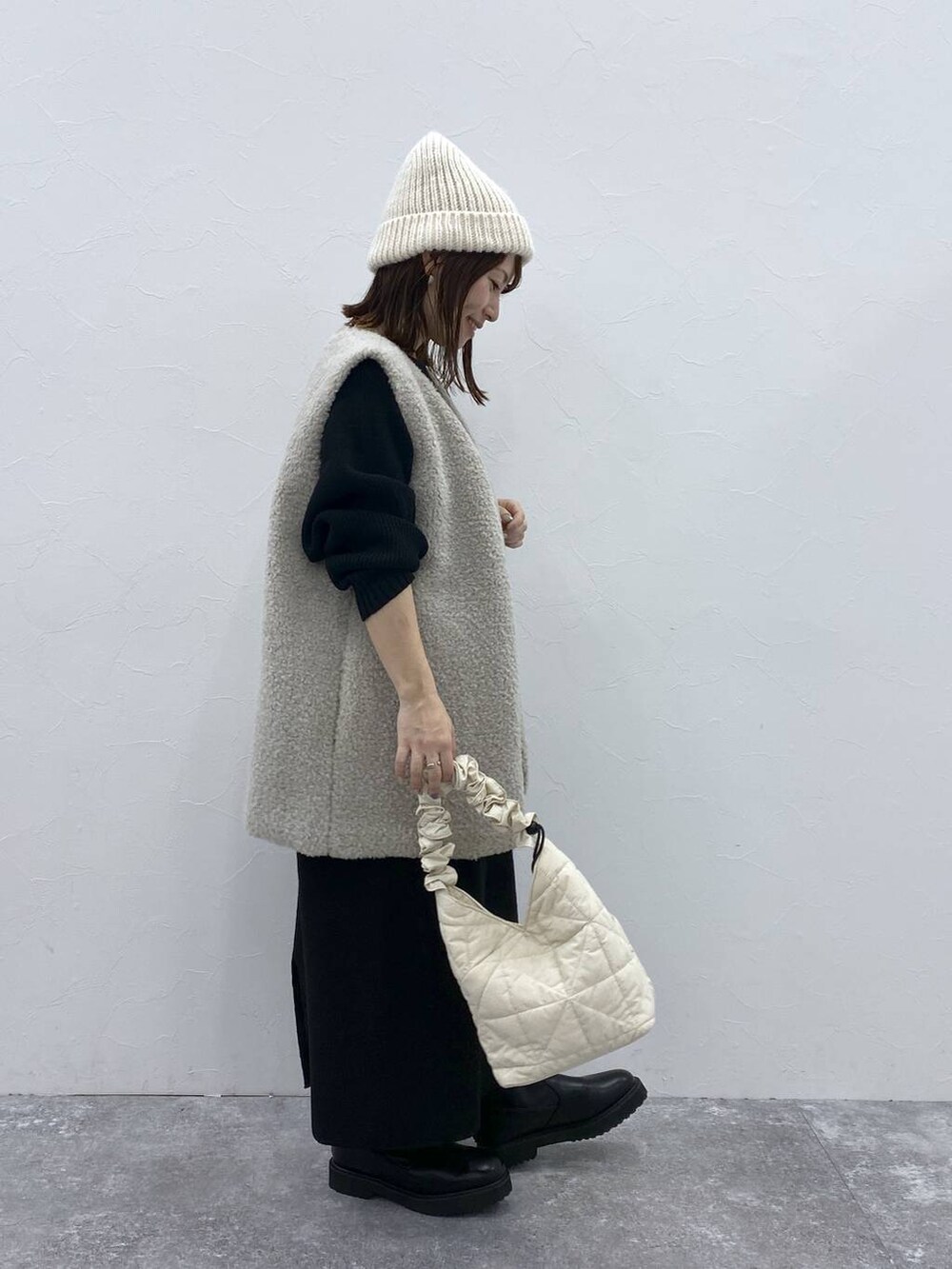 グレー系のベスト、ベージュ系のトートバッグ、ブラック系のブーツを着用したレディースの秋コーディネートの4枚目の写真