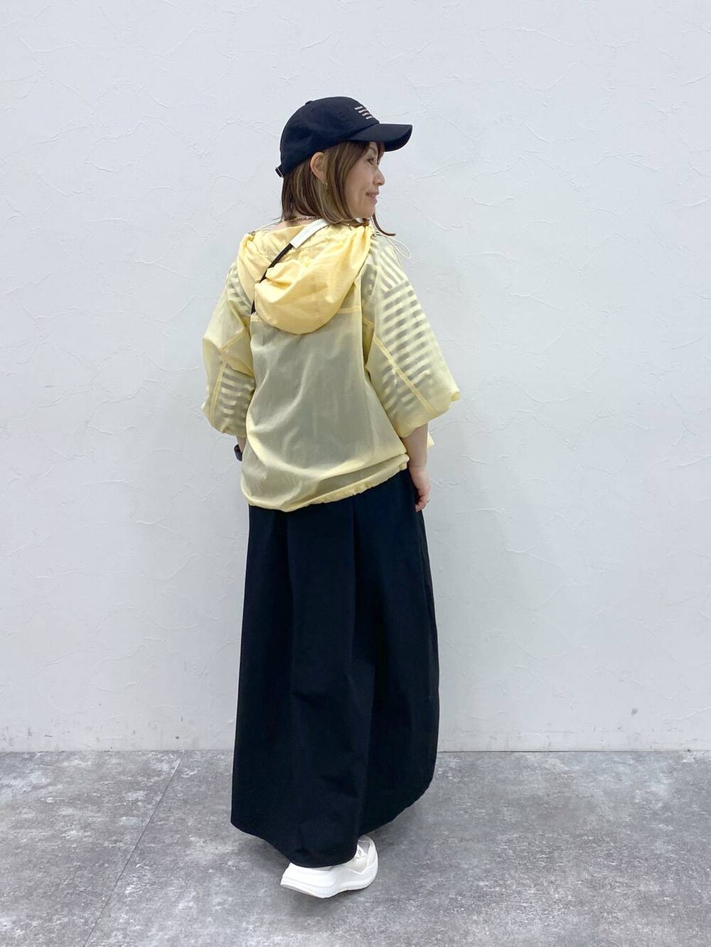 ホワイト系のスニーカー、ブラック系のキャップ、ホワイト系の財布を着用したレディースの春コーディネートの5枚目の写真