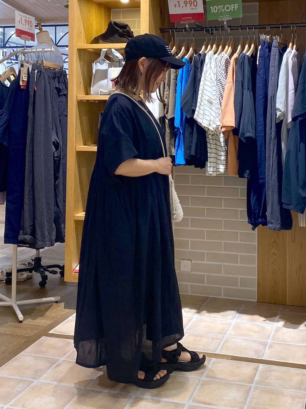 ホワイト系のショルダーバッグ、ブラック系のワンピース、ブラック系のサンダルを着用したレディースの夏コーディネートの4枚目の写真