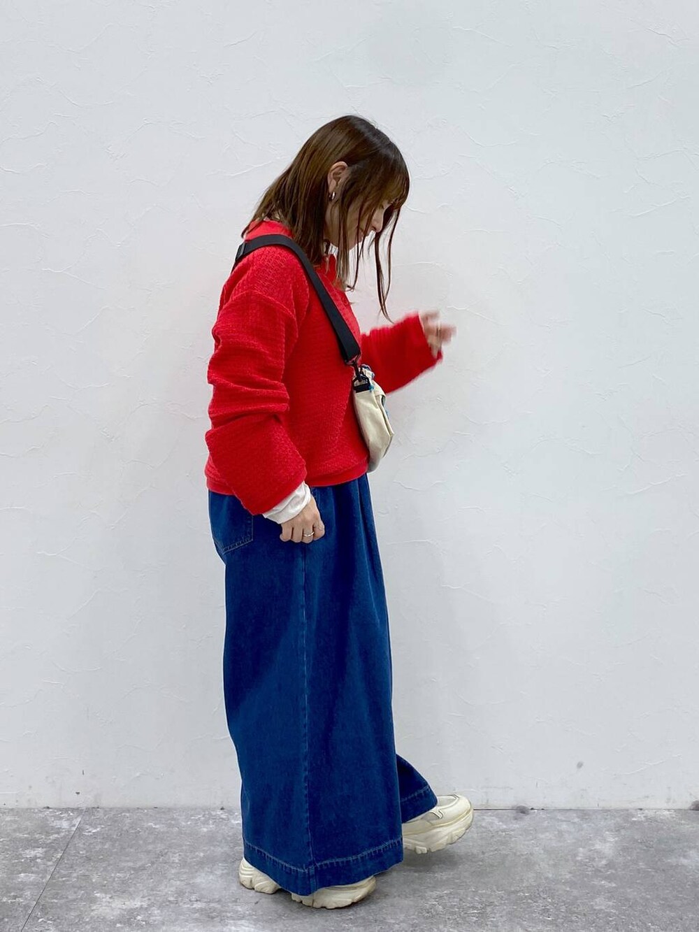 ベージュ系のショルダーバッグ、ブルー系のデニムパンツ、レッド系のカーディガン/ボレロを着用したレディースの春コーディネートの4枚目の写真