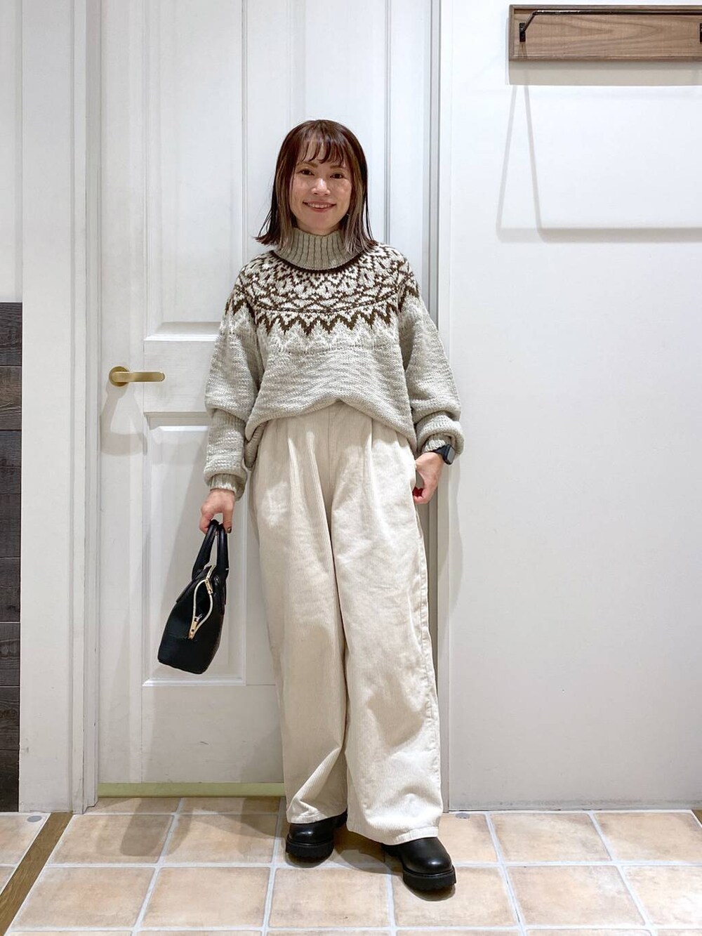 ホワイト系のその他パンツ、ブラック系のブーツ、ブラック系のショルダーバッグを着用したレディースの秋コーディネートの2枚目の写真