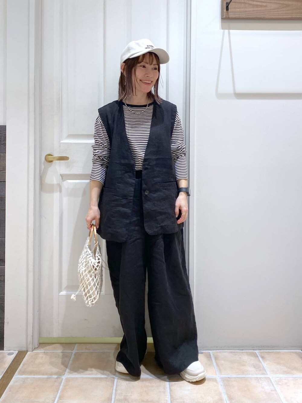 ベージュ系のスニーカー、ブラック系のその他パンツ、ブラック系のベストを着用したレディースの春コーディネートの2枚目の写真