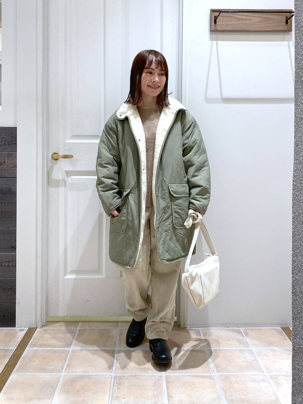 グリーン系のその他アウター、ブラック系のブーツ、グレー系のその他パンツを着用したレディースの冬コーディネートの2枚目の写真