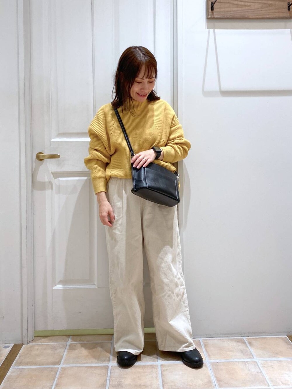 ホワイト系のその他パンツ、ブラック系のブーツ、イエロー系のニット/セーターを着用したレディースの冬コーディネートの3枚目の写真