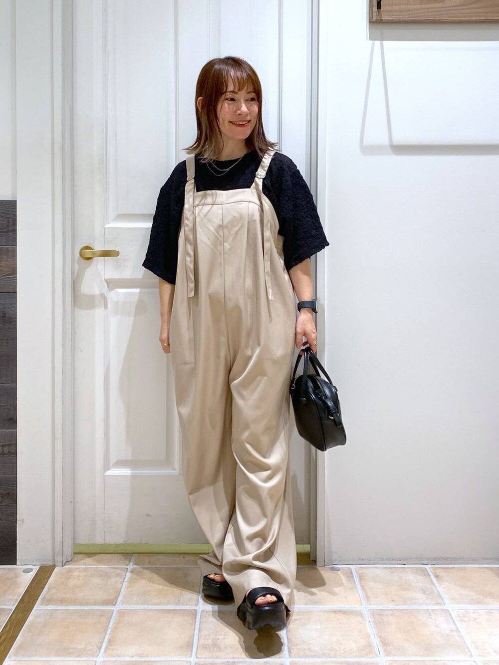 ブラック系のショルダーバッグ、ブラック系のサンダル、ブラック系のTシャツ/カットソーを着用したレディースの秋コーディネートの3枚目の写真