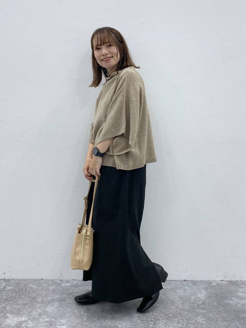 ブラック系のスカート、ベージュ系のベスト、ブラック系のブーツを着用したレディースの秋コーディネートの5枚目の写真