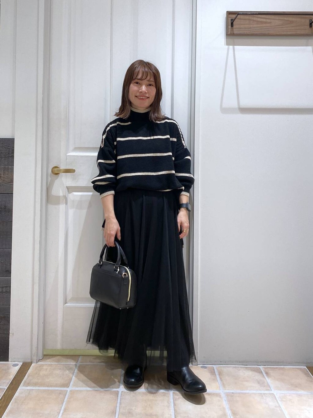 ブラック系のブーツ、その他のニット/セーター、ブラック系のスカートを着用したレディースの冬コーディネートの3枚目の写真