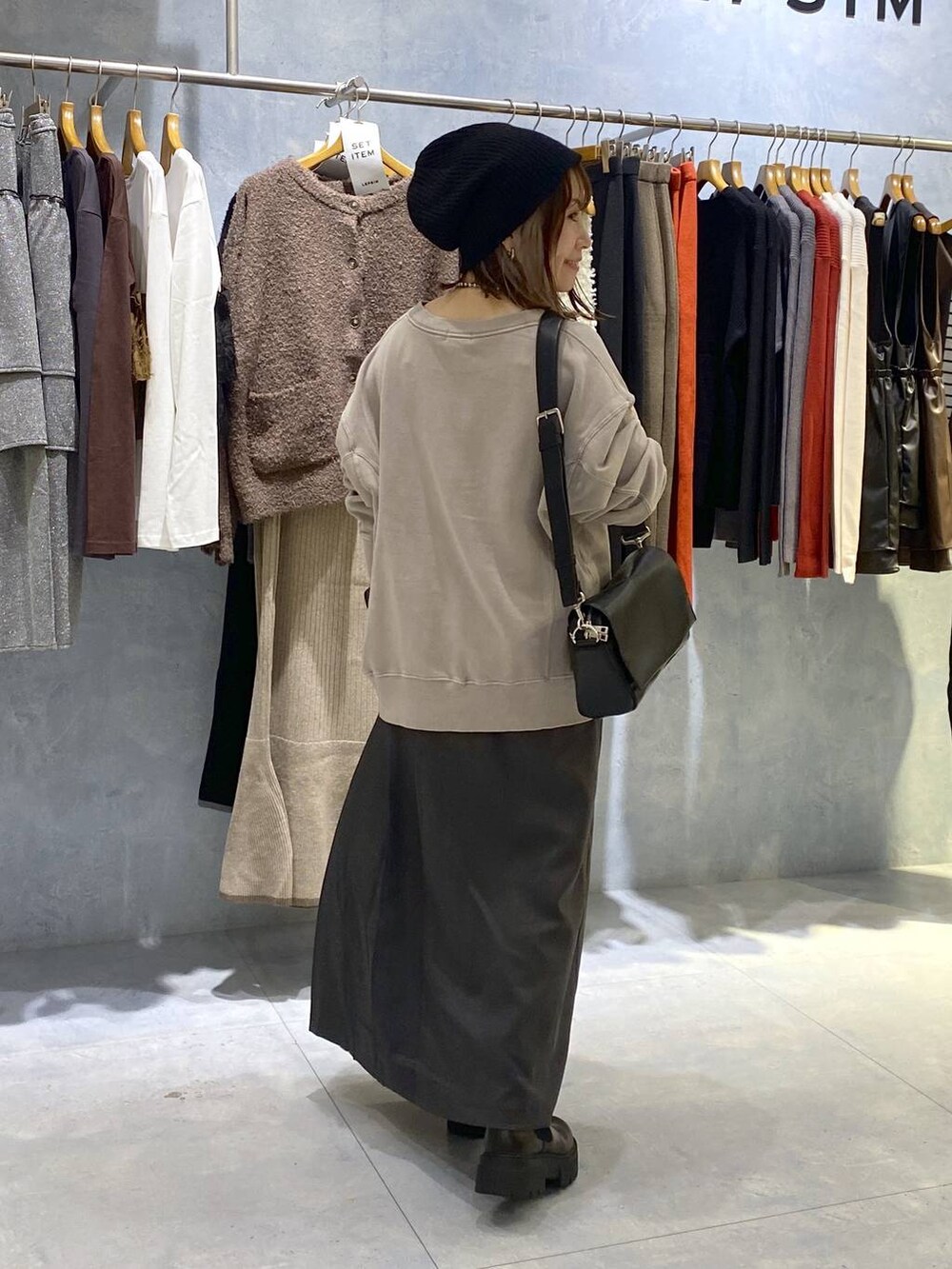 ブラック系のショルダーバッグ、ブラック系のブーツ、グレー系のスカートを着用したレディースの秋コーディネートの5枚目の写真