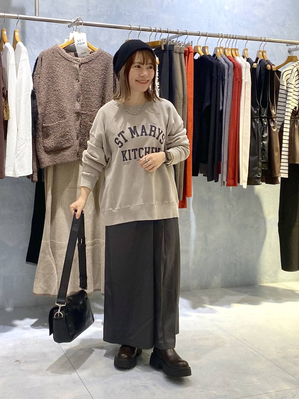 ブラック系のショルダーバッグ、ブラック系のブーツ、グレー系のスカートを着用したレディースの秋コーディネートの3枚目の写真