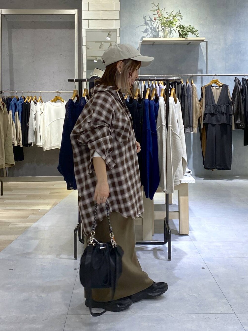 ブラック系のショルダーバッグ、ブラウン系のスカート、ブラック系のスニーカーを着用したレディースの秋コーディネートの4枚目の写真