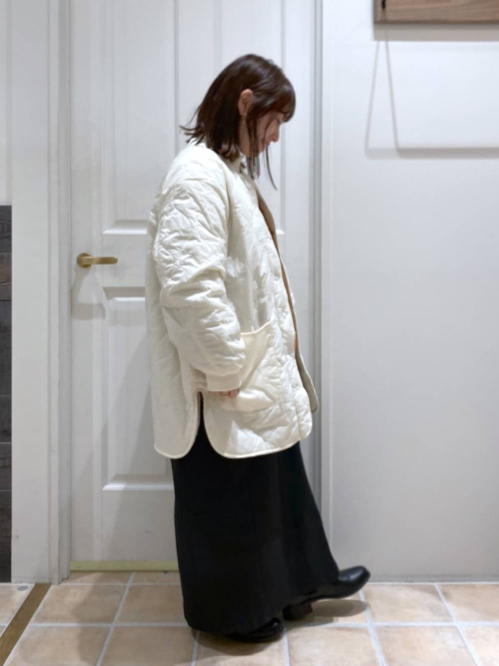 ブラック系のスカート、ホワイト系のTシャツ/カットソー、ホワイト系のノーカラーコートを着用したレディースの秋コーディネートの5枚目の写真