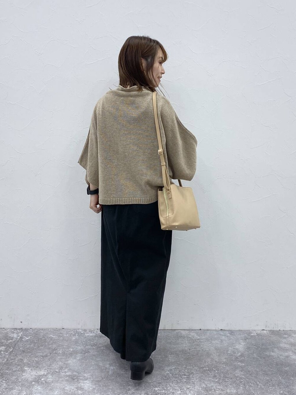 ブラック系のスカート、ベージュ系のベスト、ブラック系のブーツを着用したレディースの秋コーディネートの7枚目の写真