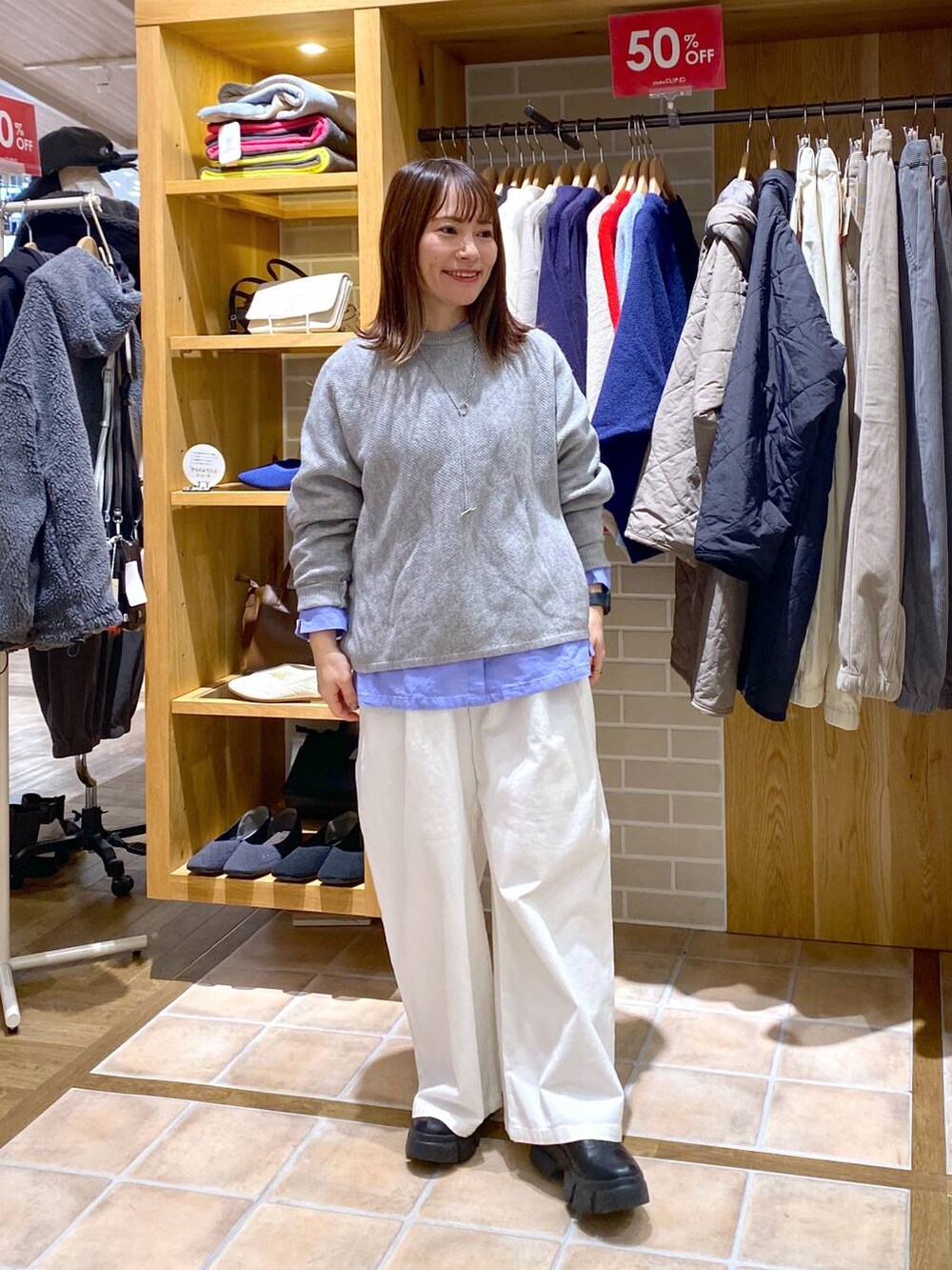 ブルー系のシャツ/ブラウス、ブラック系のブーツ、グレー系のニット/セーターを着用したレディースの冬コーディネートの3枚目の写真